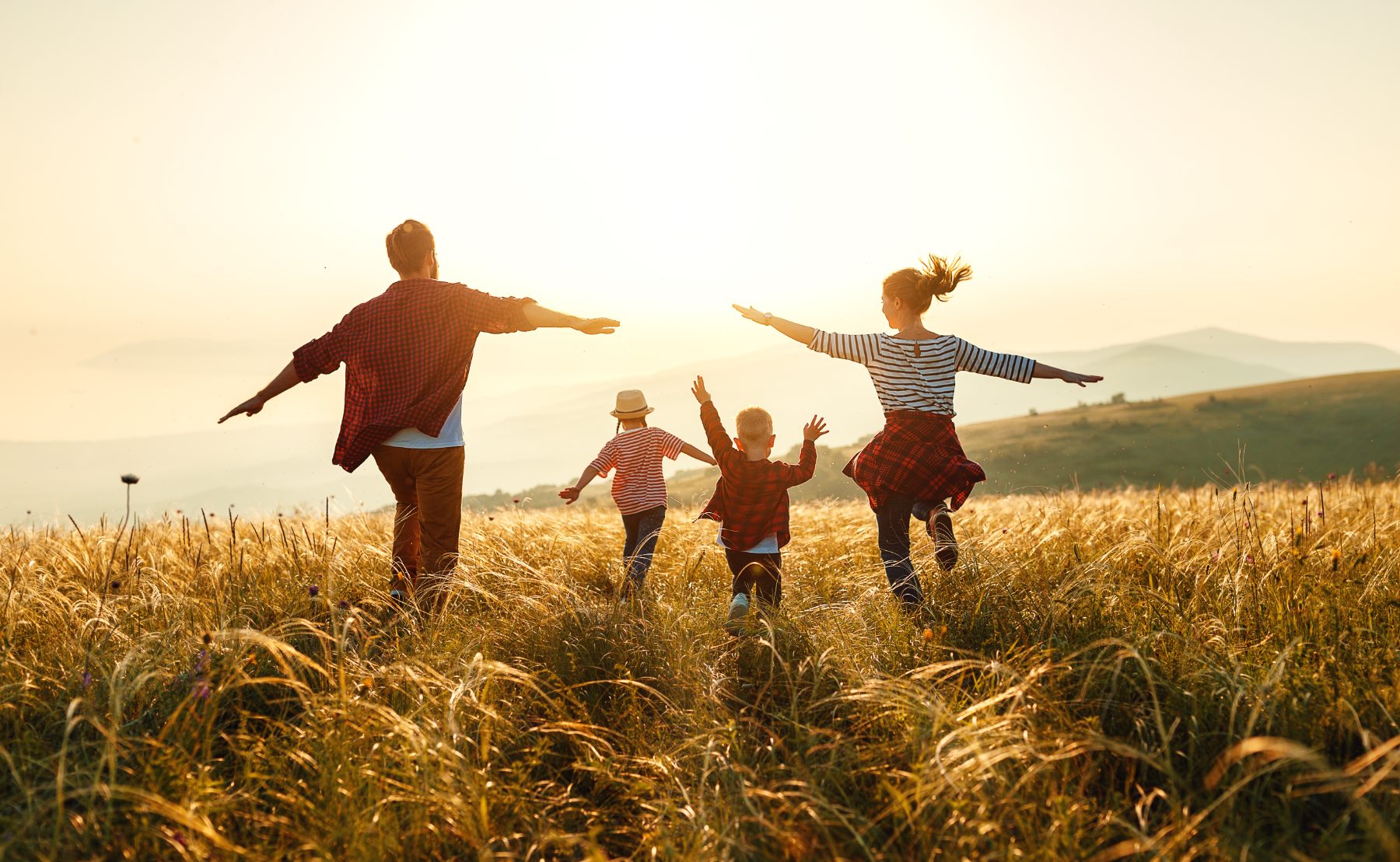 Familie läuft gemeinsam durch ein Feld im Abendlicht